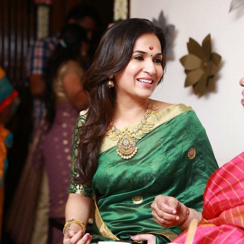 Soundarya Rajinikanth smiling in an emerald-green silk saree with an ornate gold and emerald necklace