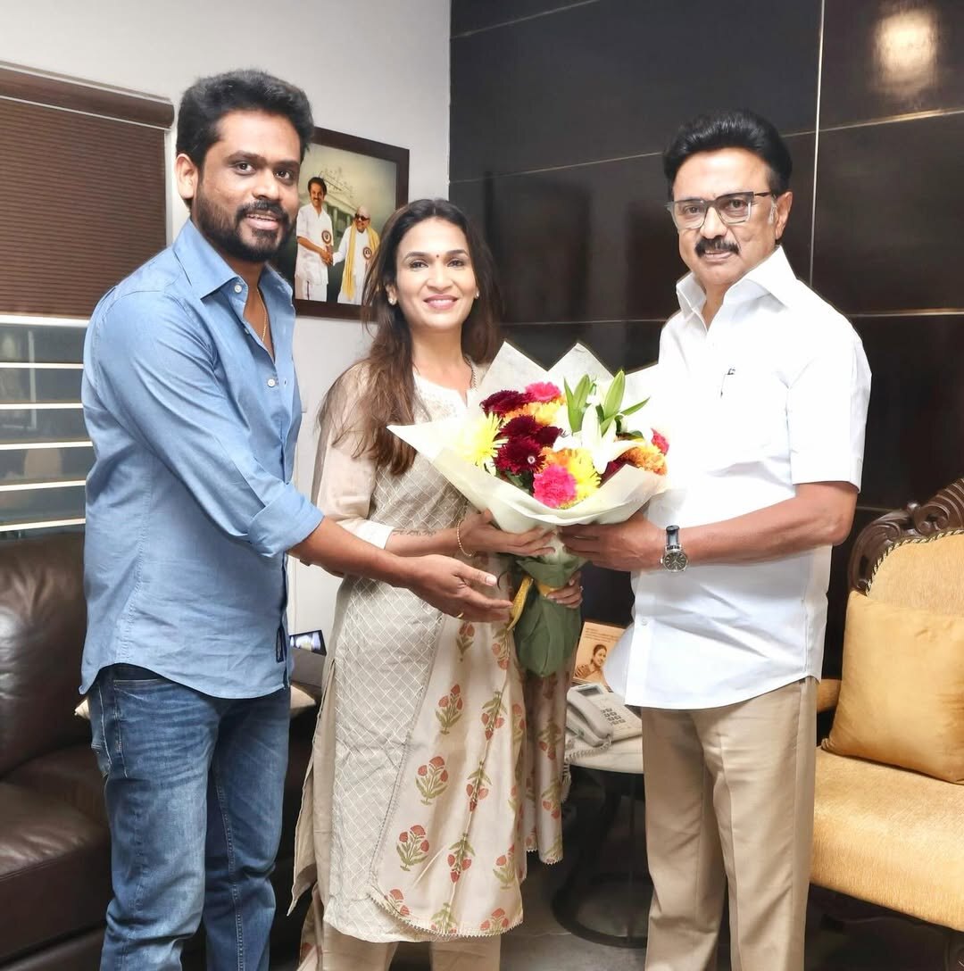 Soundarya Rajinikanth presenting a bouquet of flowers alongside a colleague during an official meeting